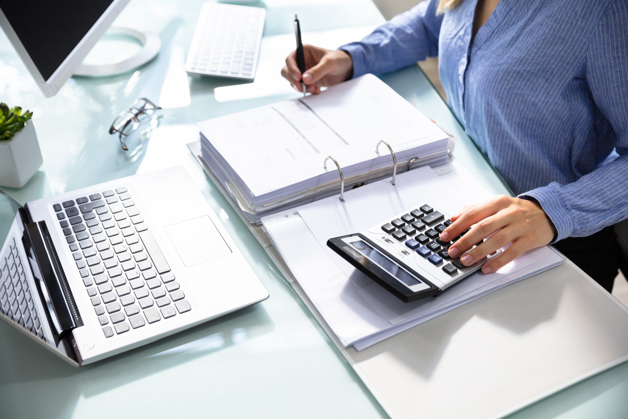 Businesswoman’s Hand Calculating Bill In Office